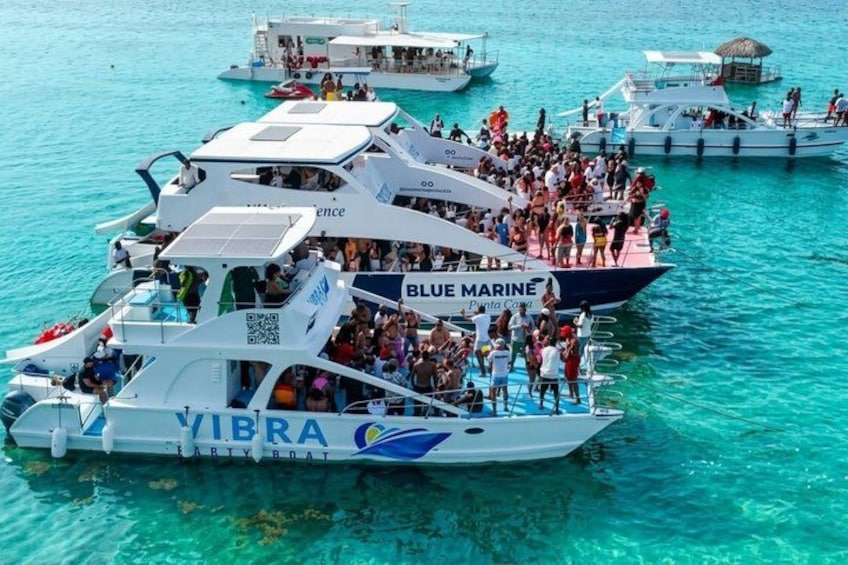 A group of boats with people on them, floating on clear blue water. 2