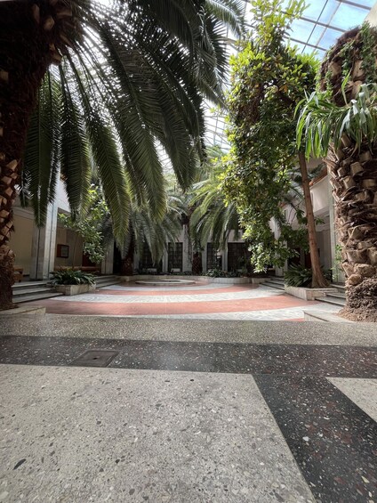 A courtyard with palm trees, a tiled floor, and a glass ceiling. 2