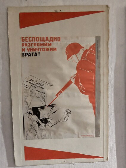 A poster with a soldier pointing a gun at a person, and text in a foreign language. 4