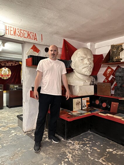 A man standing in front of a display with a bust, books, and memorabilia. 5