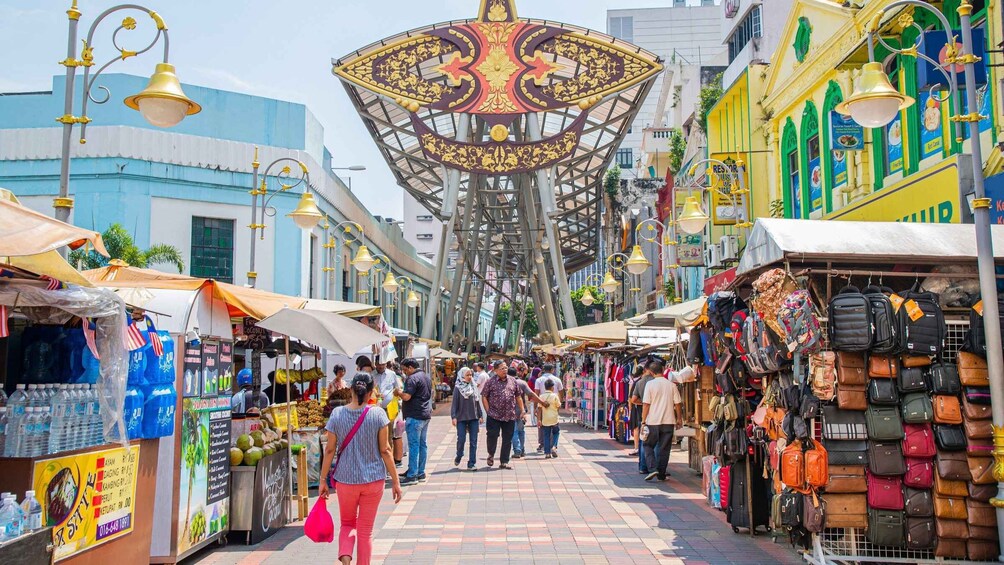 A bustling market street with vendors selling fruits, beverages, and bags. 2