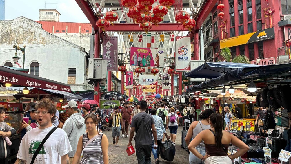 A bustling street market with various stalls and shops, including a sign for 'Apple Juice' and 'Pineapple Juice'. 3