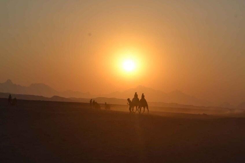 A desert landscape with a sunset, silhouettes of people on horseback, and distant mountains. 1