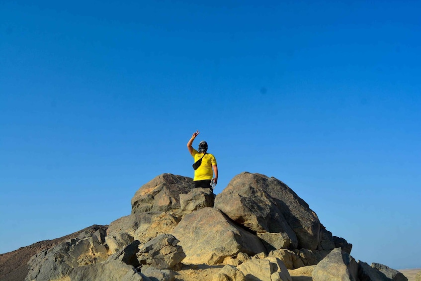 A person standing on a rocky peak with a clear blue sky. 1