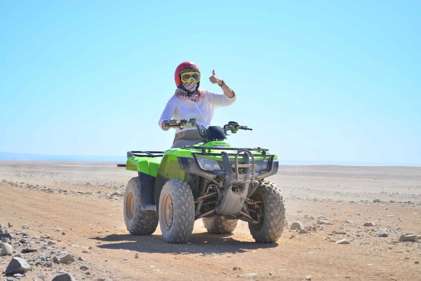 A person riding a green ATV in a barren landscape. 2