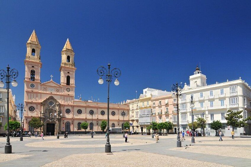 A plaza with a prominent church with two towers, surrounded by buildings and street lamps. 4