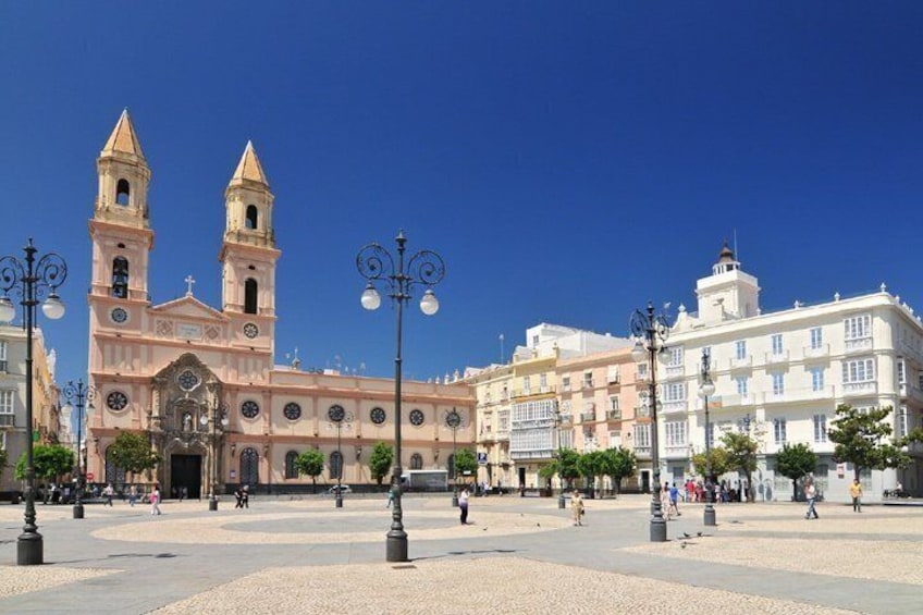 A plaza with a historic church featuring two towers, surrounded by buildings and street lamps. 4
