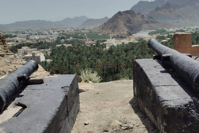 Una fortaleza histórica con cañones que domina un paisaje urbano con montañas al fondo. 3
