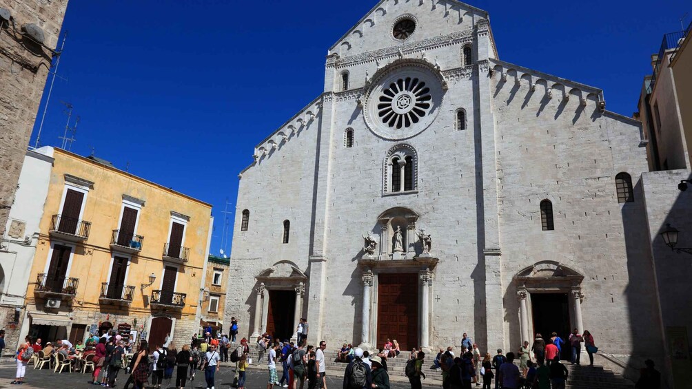 A historic church with a large circular window and a crowd of people in front. 1