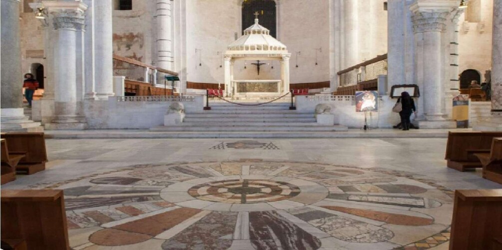 A church interior with a central altar, columns, and a mosaic floor. 2
