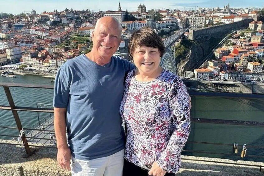 A couple standing on a bridge with a cityscape in the background. 5