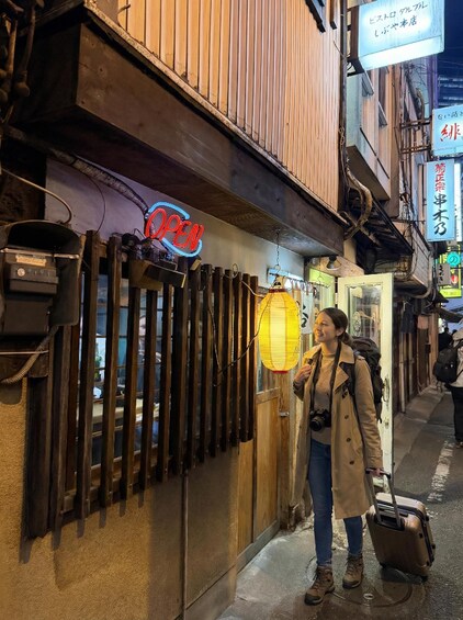 A person standing outside a building with a neon 'OPEN' sign, holding a lantern. 3