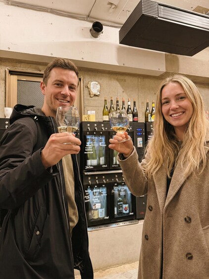 Two people holding wine glasses in a wine cellar with wine racks in the background. 1