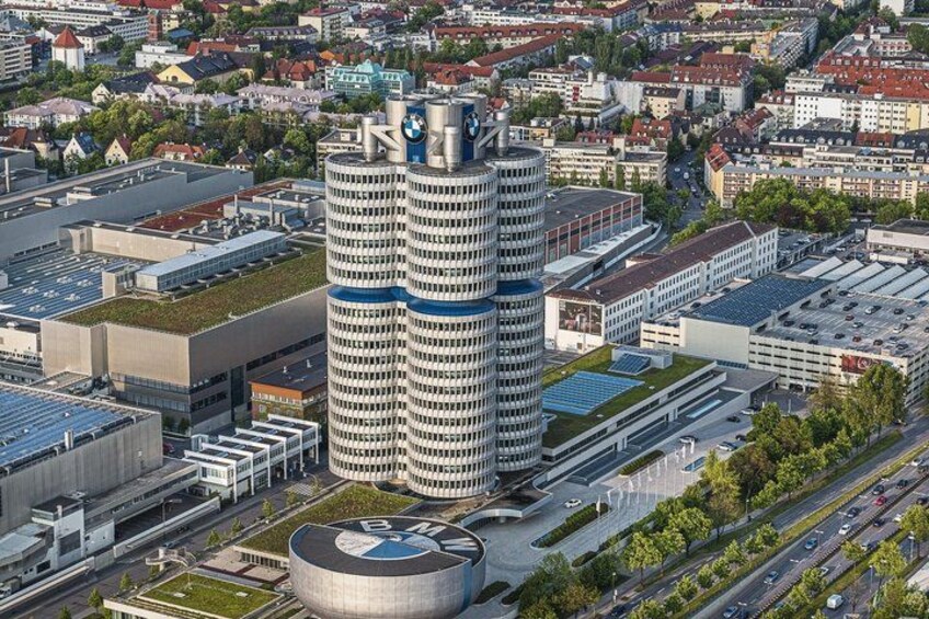 A tall building with a circular top, surrounded by other buildings and roads. 2