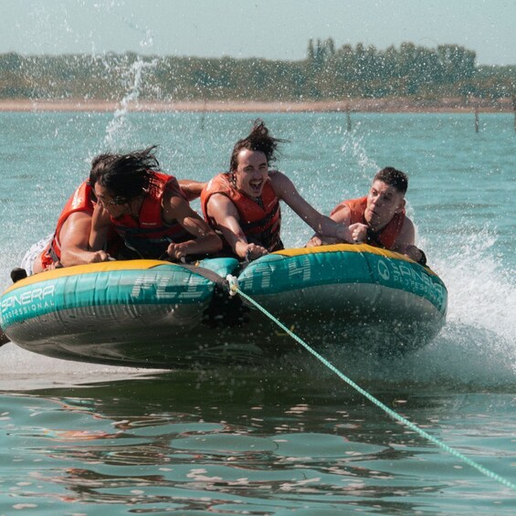 Three people on a watercraft, wearing life jackets, with water splashing around. 3