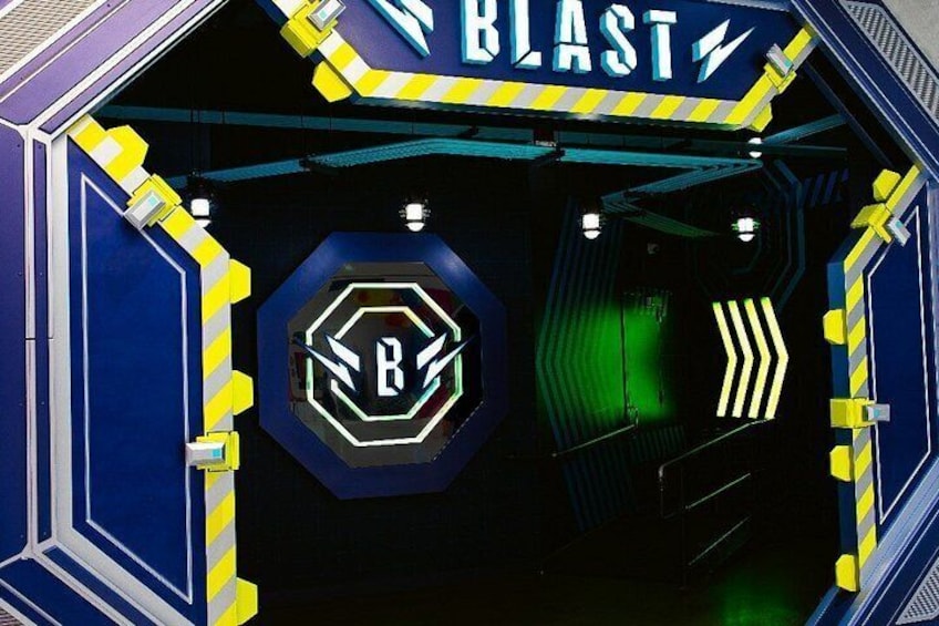 Entrada a un túnel con un letrero de neón que dice 'BLAST' y un logotipo hexagonal con una 'B' en el centro. 2