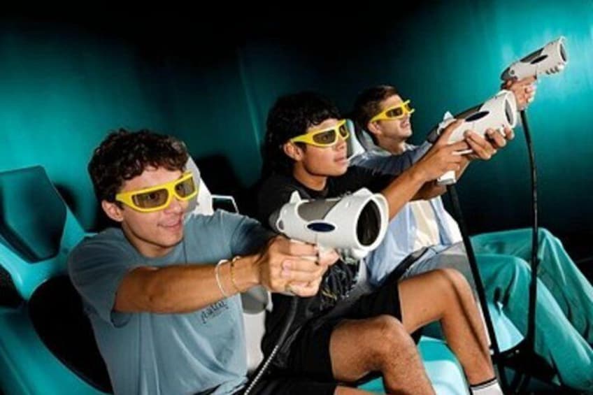Three people wearing yellow glasses, holding white handheld devices, seated on teal chairs. 3