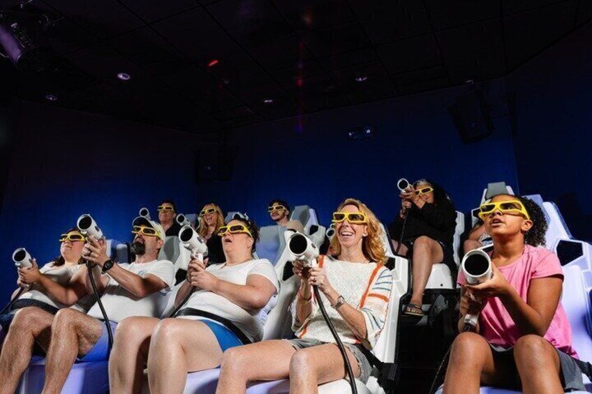 People seated in a theater with headsets, wearing yellow sunglasses. 1