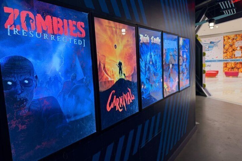 Una serie di locandine cinematografiche su un muro, con titoli come 'Zombies [RESURRECTED]' e 'Carpocalypse'. 3