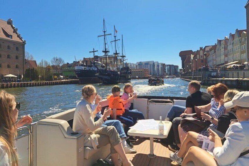 People on a boat, a tall ship, and buildings along a canal. 4