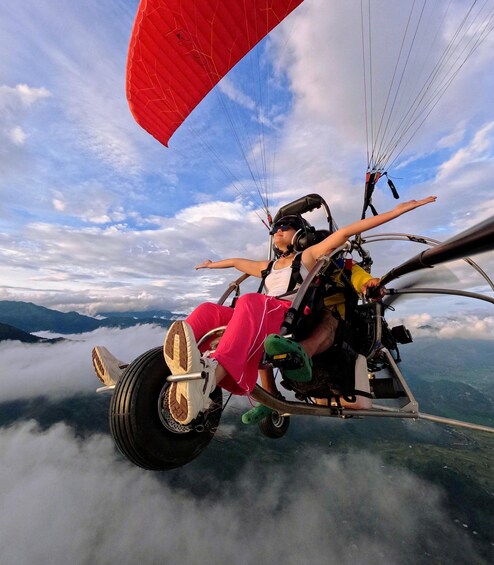 A person paragliding above clouds with mountains in the background. 1