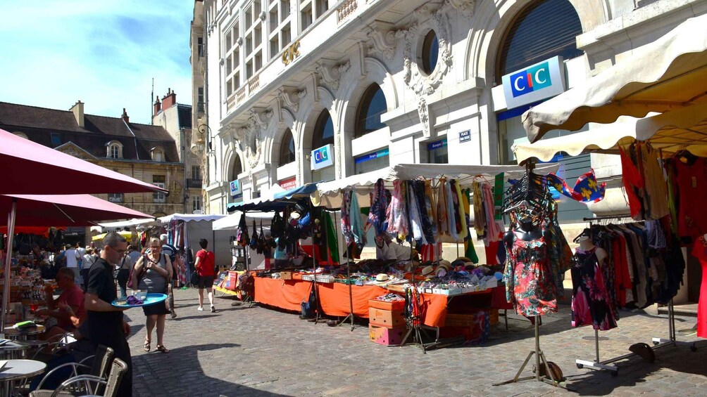 A bustling outdoor market with stalls selling clothes and accessories. 5