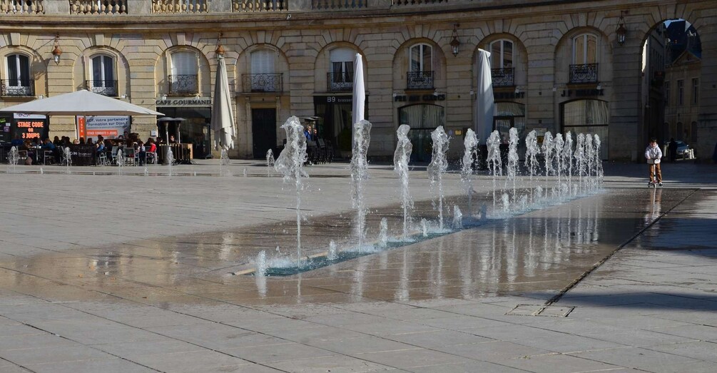 A public square with a fountain, buildings, and a café. 4