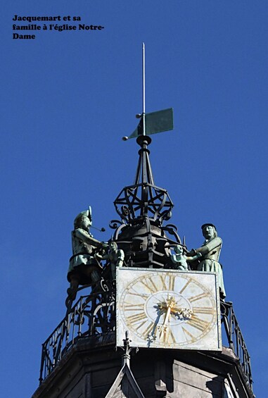 A clock tower with a statue of a man playing a trumpet and another statue of a woman. 2
