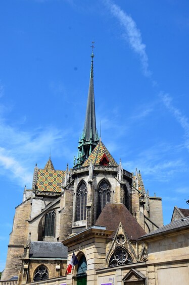 A historic church with a tall spire and colorful patterned roof. 1