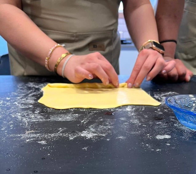 A person rolling out dough on a floured surface. 5