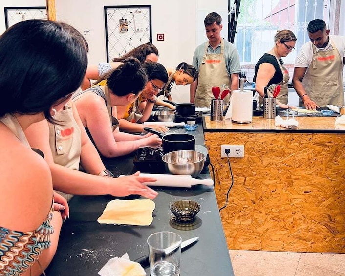 A group of people engaged in a cooking class, with cooking utensils and ingredients on the counter. 4