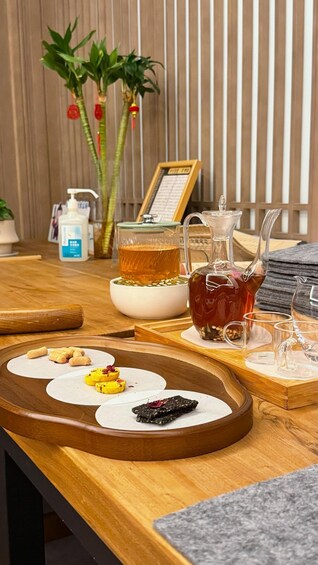 A wooden table with a tea set, a bottle of hand sanitizer, and a framed menu. 1