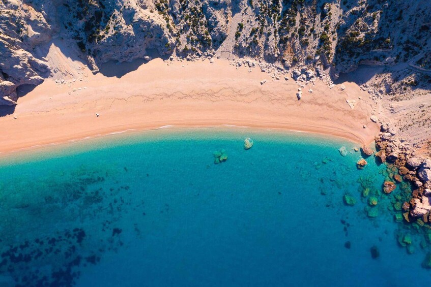 A coastal beach with clear turquoise waters and rocky outcrops. 5