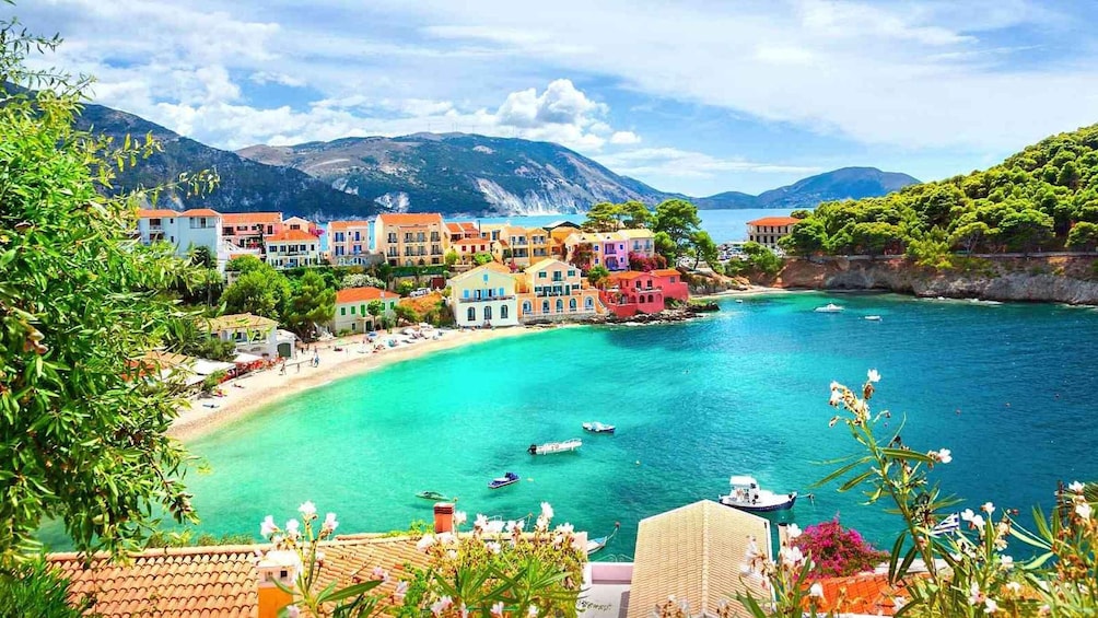 A coastal town with colorful buildings, a beach, boats, and mountains in the background. 1