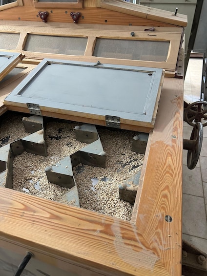 A wooden structure with a metal tray and a wheel mechanism. 5