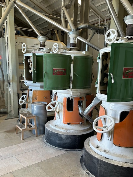 Industrial machinery with green and orange components, pipes, and a small wooden stool. 3