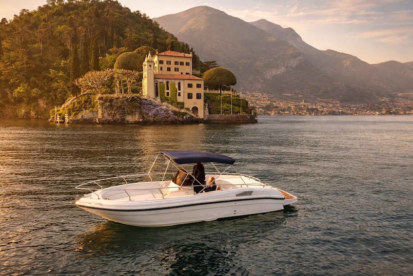A boat on calm water with a mountainous landscape and a building in the background. 1
