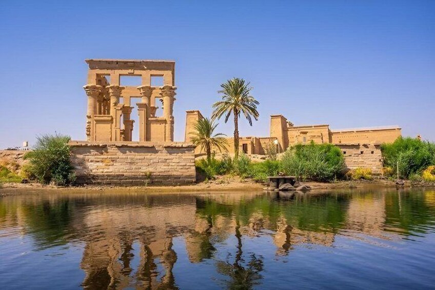 Ancient Egyptian ruins by a calm river with palm trees. 1