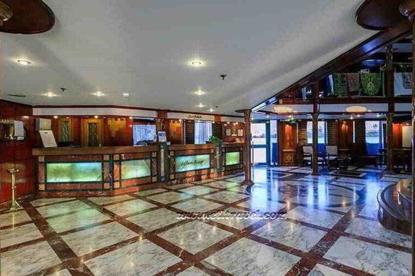 A lobby with a checkered floor, reception desk, and wooden paneling. 2