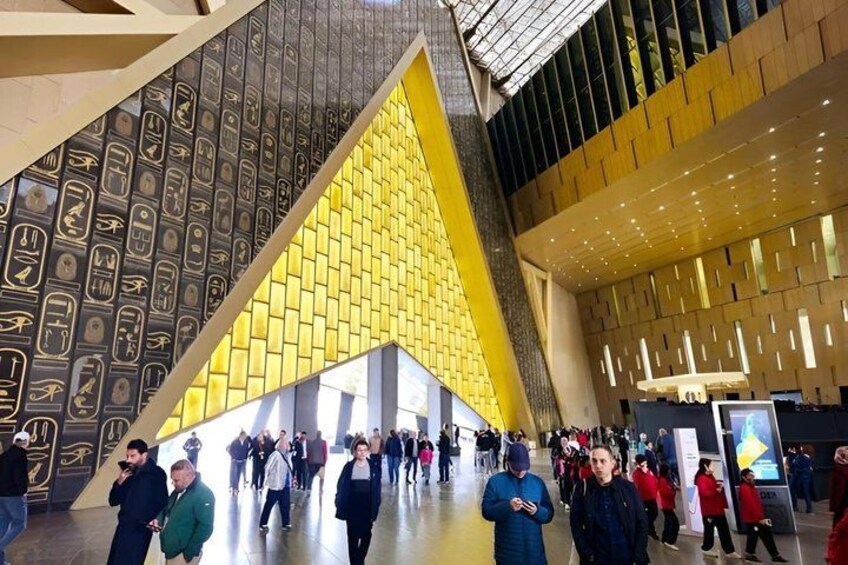 A modern building with a yellow triangular facade and hieroglyphic patterns on the walls. 5
