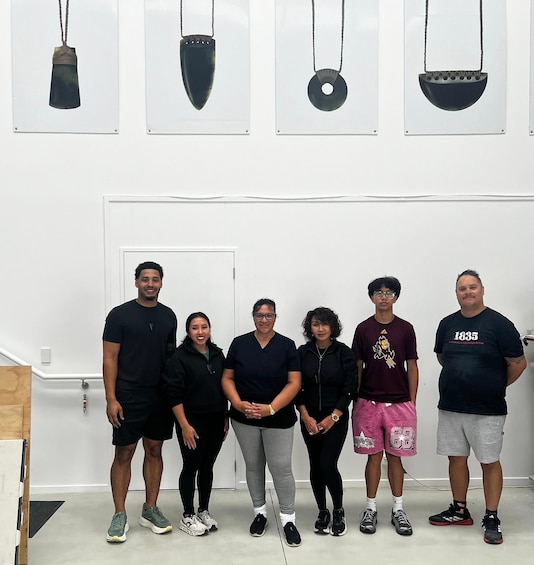 A group of people standing in front of a wall with various hanging objects. 3