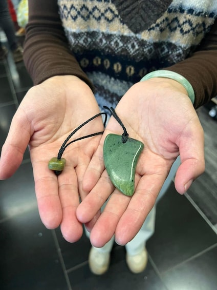 A person holding two green stones with black strings. 2