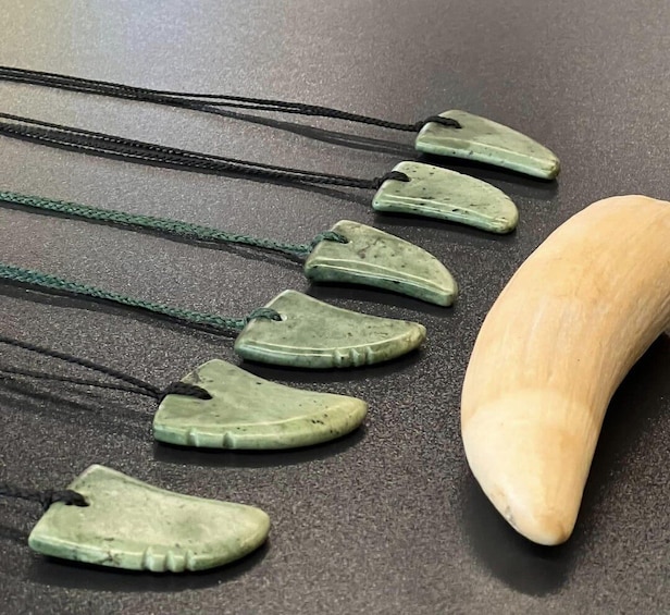 A collection of green jade shoe-shaped pendants with black cords, arranged on a dark surface. 1