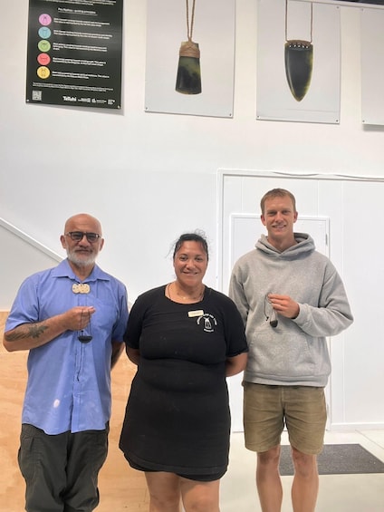 Three people standing in a room with a wall-mounted display and a door in the background. 5