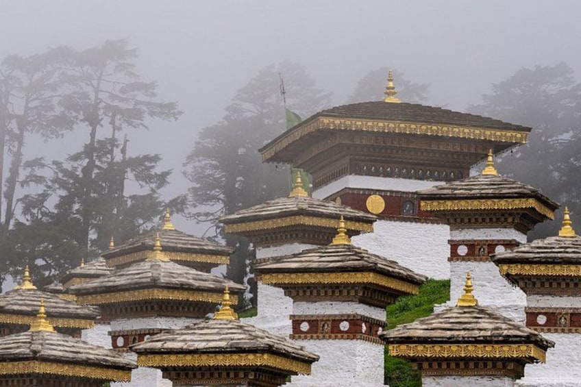 A series of snow-covered pagodas with golden roofs, set against a foggy mountainous backdrop. 2