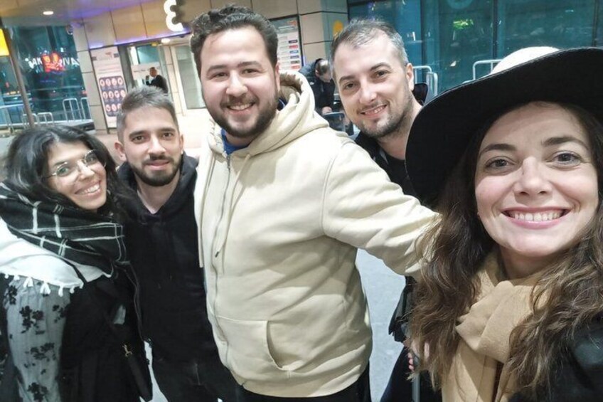Un grupo de personas de pie en un entorno urbano, con un edificio de fachada de vidrio al fondo. 2