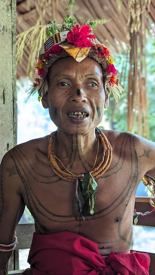 A person with tribal tattoos, wearing a beaded necklace and a floral headdress. 4