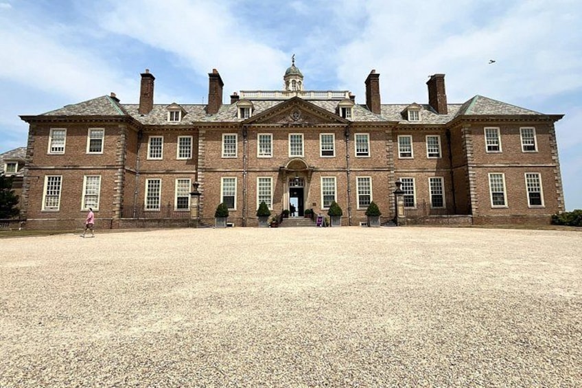 A large brick building with a symmetrical facade, multiple chimneys, and a central entrance with steps leading up to it. 2