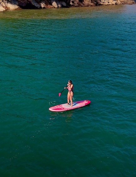 A person paddleboarding on a turquoise body of water. 1
