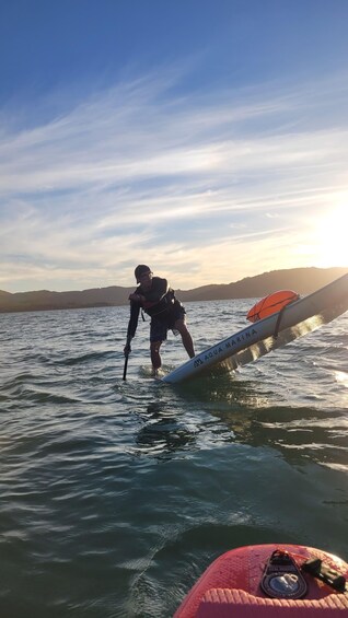 A person paddleboarding on a body of water with a surfboard. 3